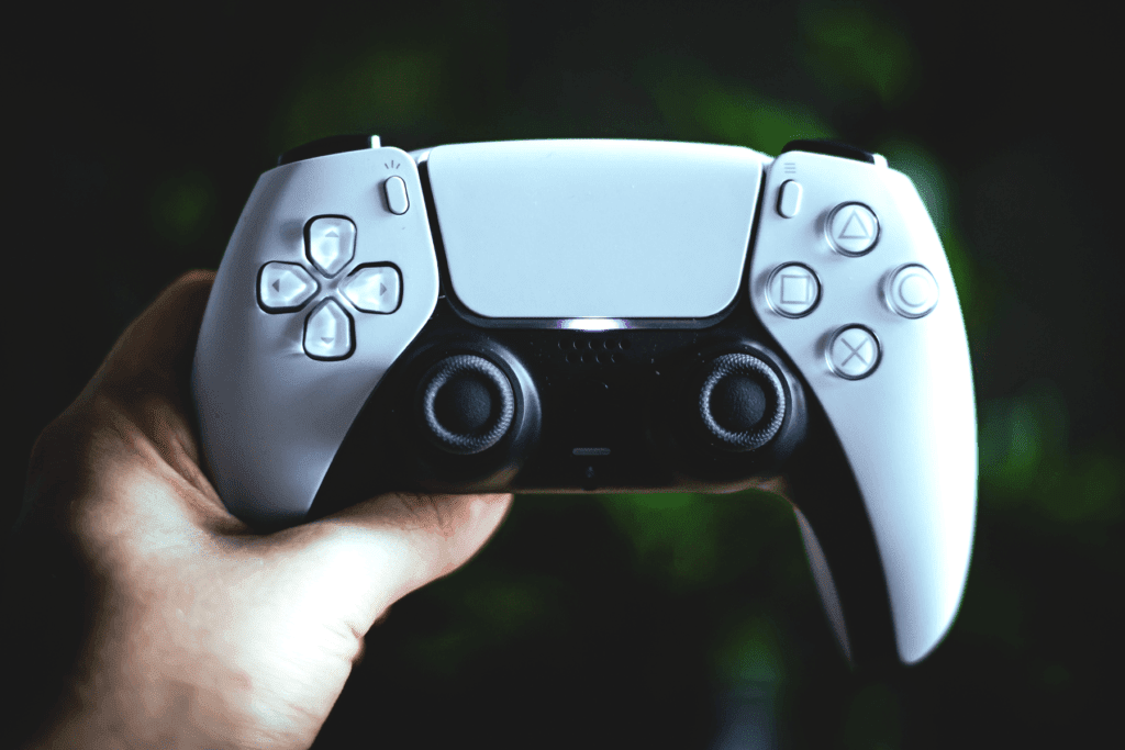A person holds a white PlayStation 5 controller their hands; decorative image to illustrate PS5 security tips for safer gaming.